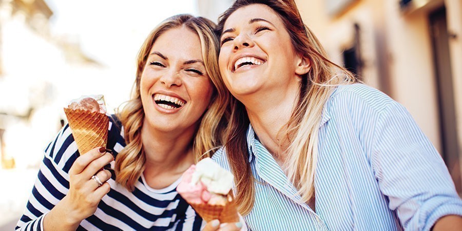 Due ragazze sorridono e mangiano due gelati